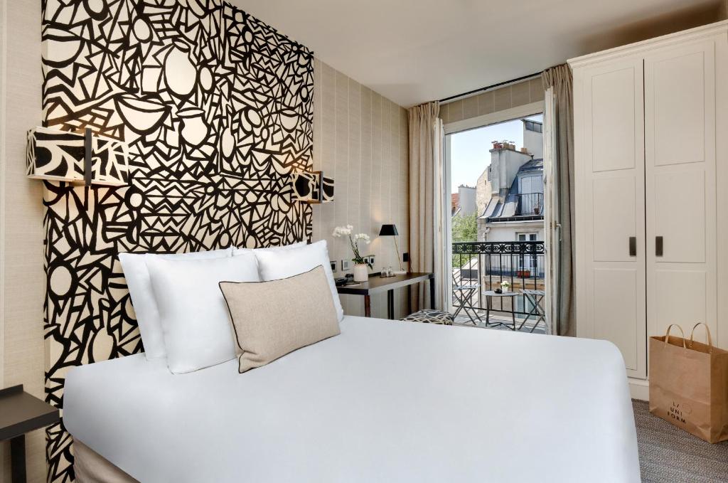 1 dormitorio con cama blanca y pared en blanco y negro en Le Senat, en París