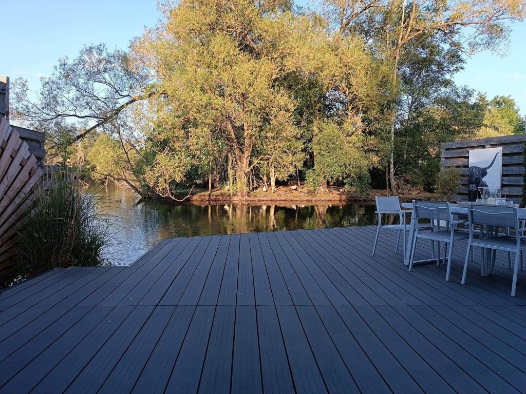 a wooden deck with chairs and a table next to a river at Time 2 Relax chalet aan het water in Geel