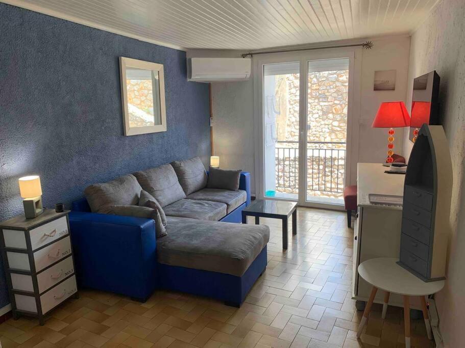 un salon avec un canapé bleu et une télévision dans l'établissement Le colibri, à Lapalme