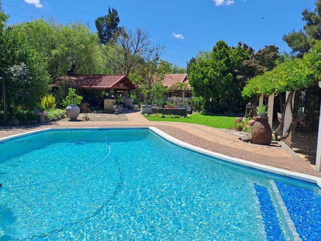 a large blue swimming pool in front of a house at Gabbys Cottage Guesthouse in Bloemfontein