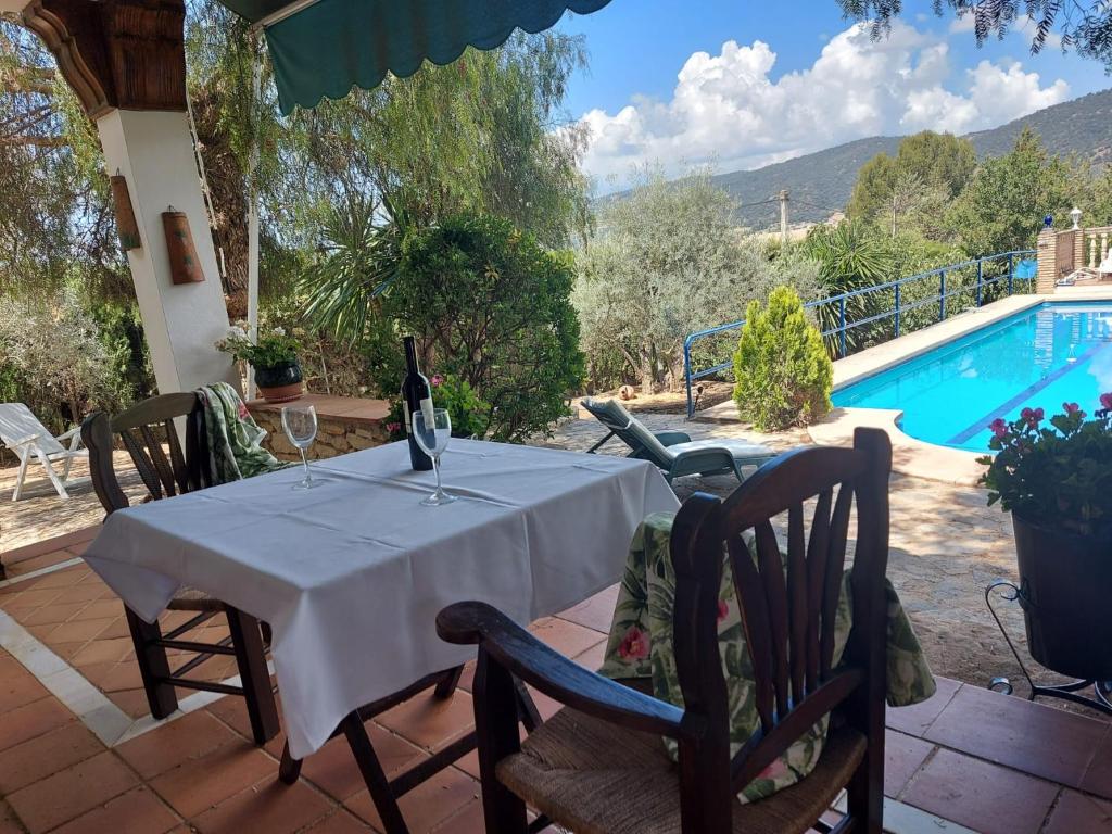 a table with wine glasses and chairs next to a swimming pool at Casa Rural El Olivar Ronda in Arriate