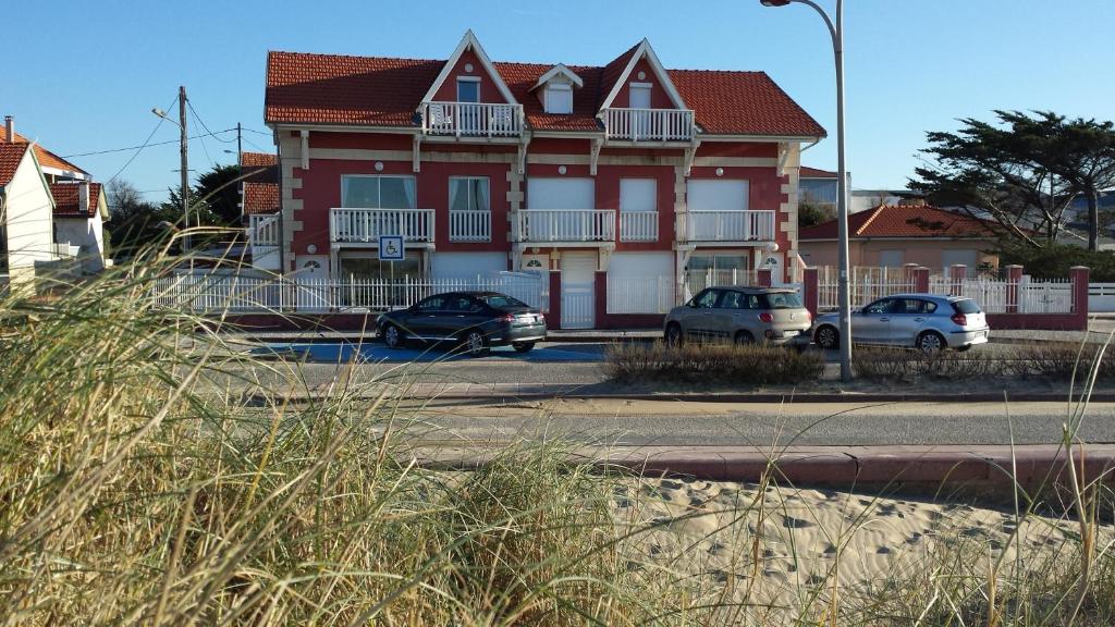 a red and white house with cars parked in front of it at Joussac Côté Plage - Protocole sanitaire strict in Soulac-sur-Mer