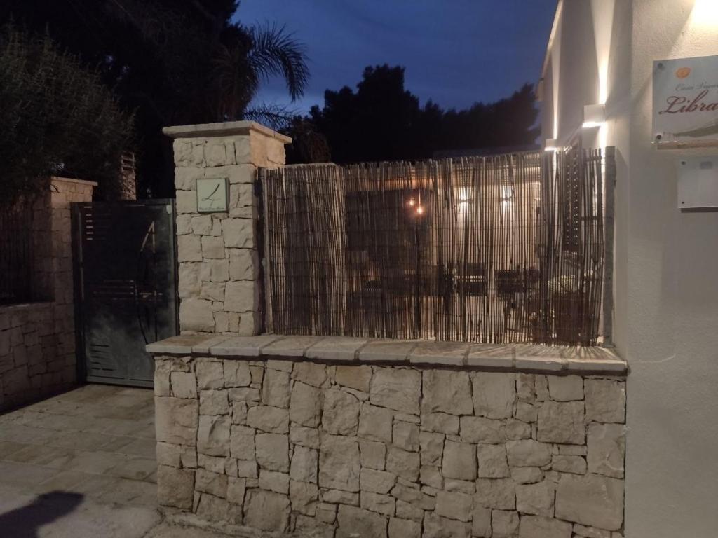 una recinzione di pietra di fronte a una casa di notte di Librari - Quality confort a Torre Ovo