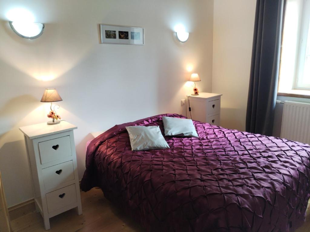 ein Schlafzimmer mit einem lila Bett und zwei Nachttischen in der Unterkunft La Maison près du ruisseau in Fenioux