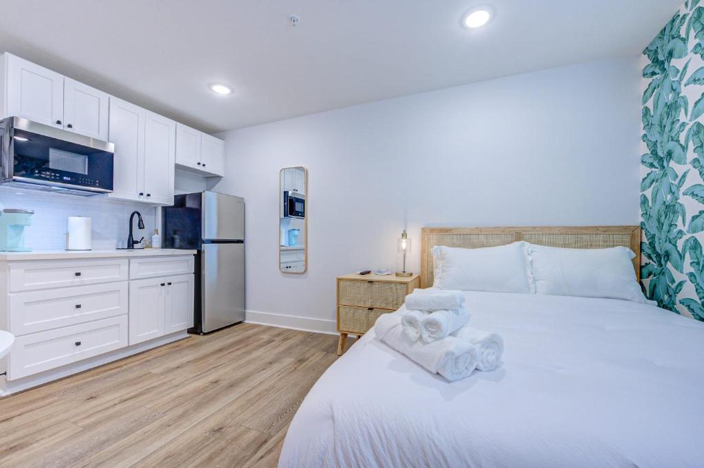 a bedroom with a white bed and a kitchen at Caribbean Sea Studio Apartment in Galveston