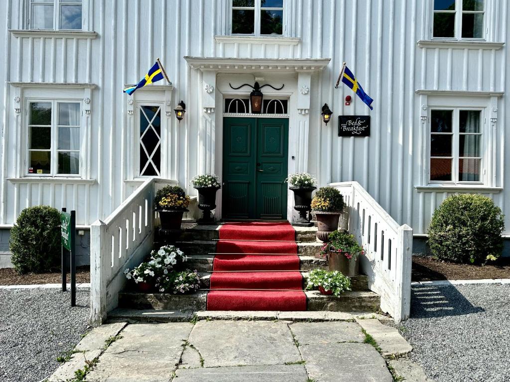 a white house with a green door and a red carpet at Kinna Bed & Breakfast in Kinna