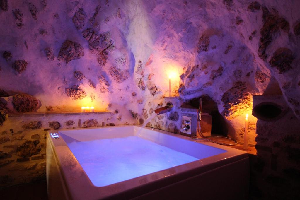 Cette chambre dispose d'une grande baignoire et d'un mur en pierre. dans l'établissement Santo'S House Luxury - idromassaggio e doccia emozionale, à Santo Stefano di Sessanio