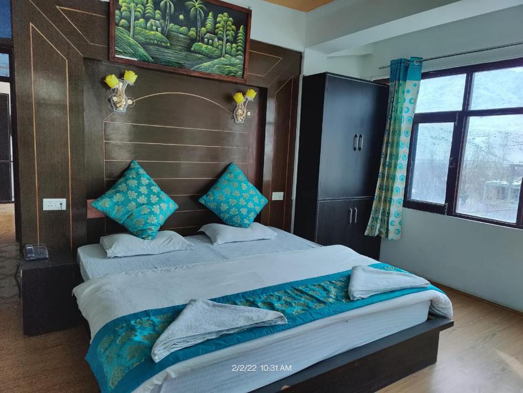 a bedroom with two beds with blue pillows at The Indian Kargil in Kargil