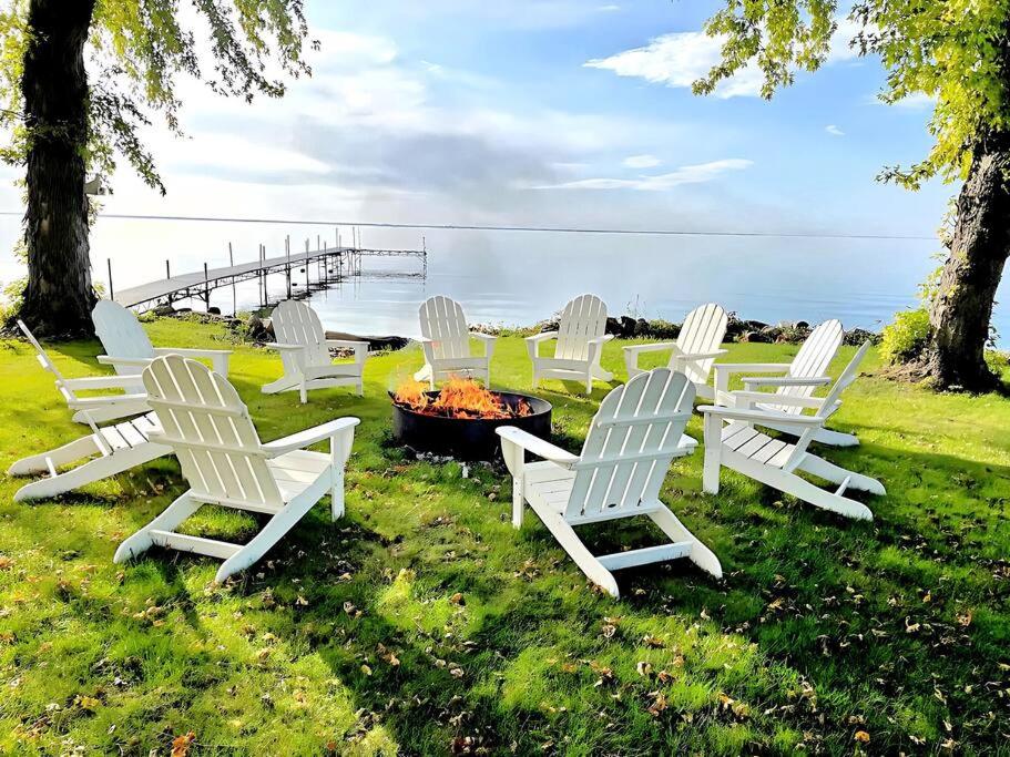 un grupo de sillas blancas sentadas alrededor de una hoguera en Lake Cottage with Garage, en Malone