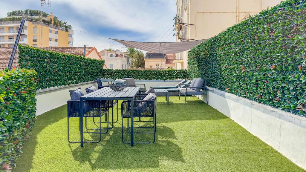 une terrasse avec des tables et des chaises et une haie dans l'établissement Le Riviera by Winsome Destination, à Cannes