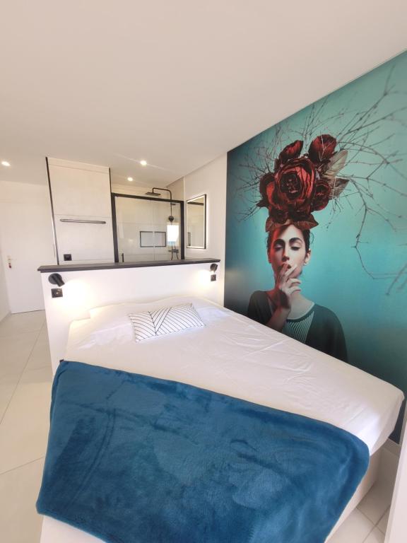 une chambre avec un lit avec un tableau sur le mur dans l'établissement Blue Sand Luxe Vue Mer - Village Naturiste Résidence Héliopolis, au Cap d'Agde