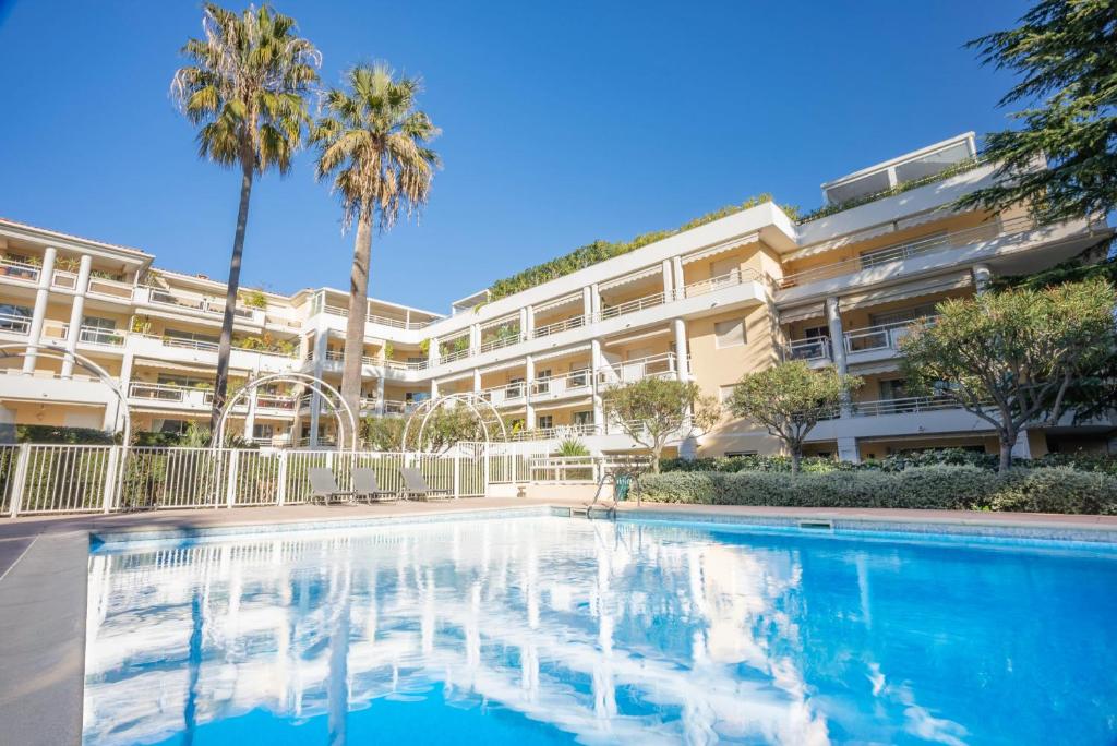 una piscina frente a un edificio con palmeras en Le First by Winsome Destination, en Cannes
