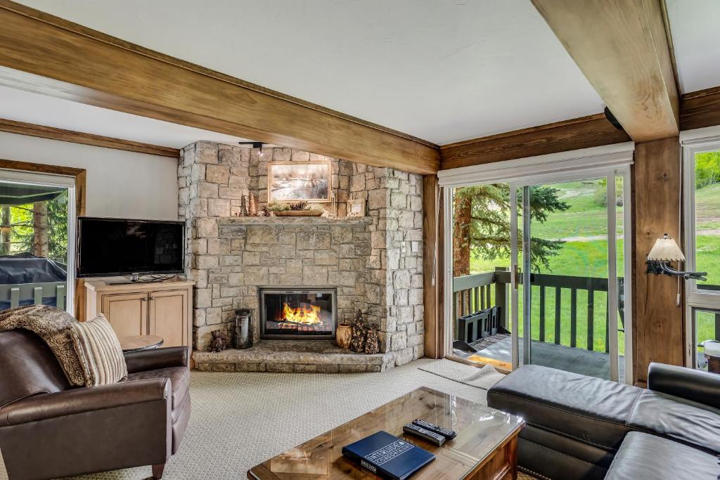 a living room with a stone fireplace in a house at Interlude Condominiums 2-Bedroom Unit 205 in Snowmass Village