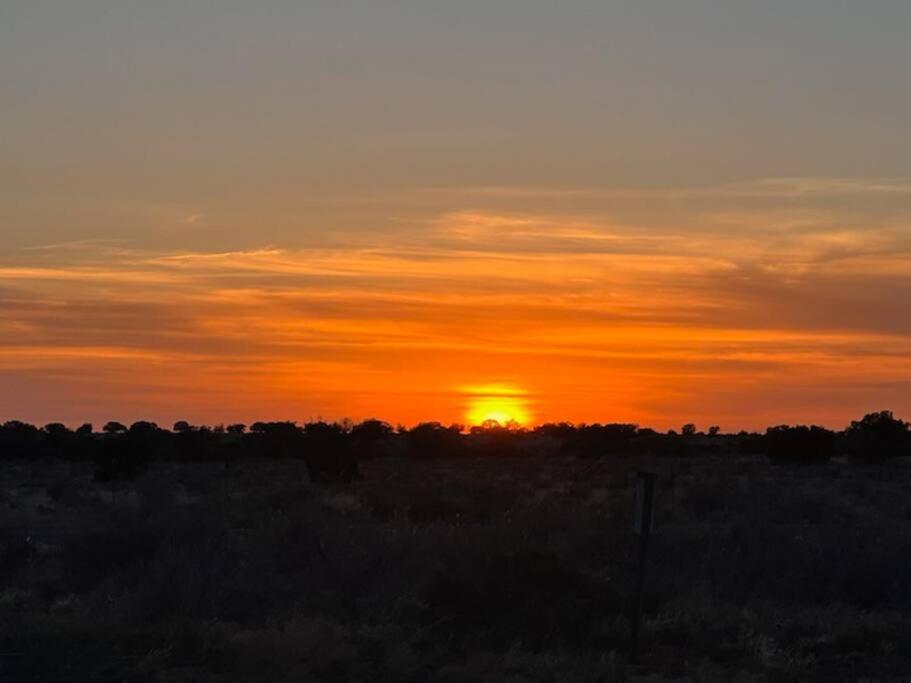 a sunset in a field with the sun in the sky at Grand Canyon Cabin, Breathtaking sunsets/sunrises!! in Valle