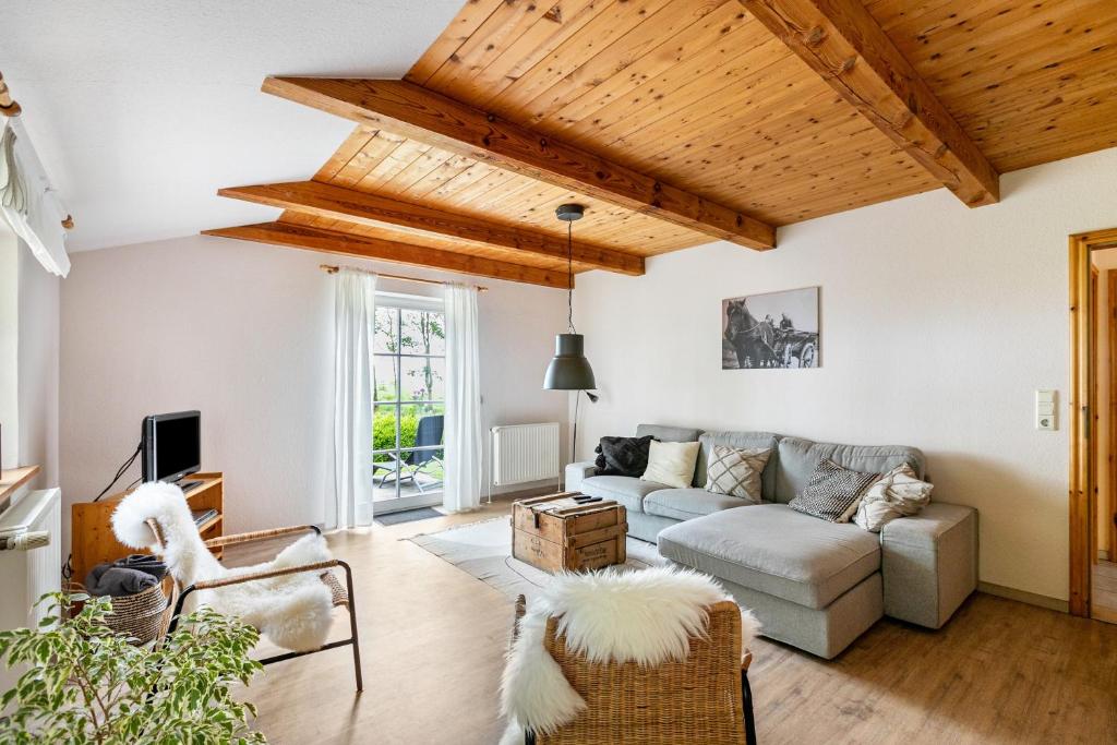 a living room with wooden ceilings and a couch at Ferienhaus Landleben und Meer in Tetenbüll