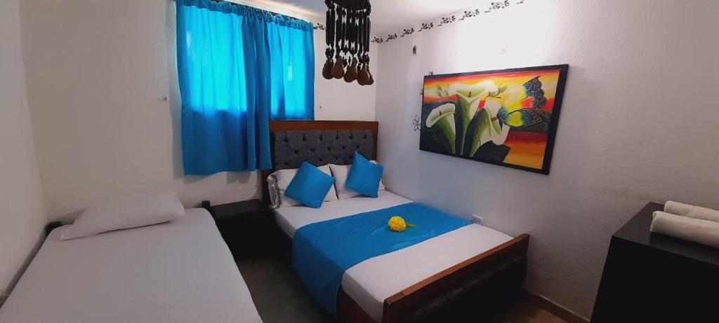 a bedroom with two beds and a painting on the wall at Hotel Playa Paraiso in Dibulla