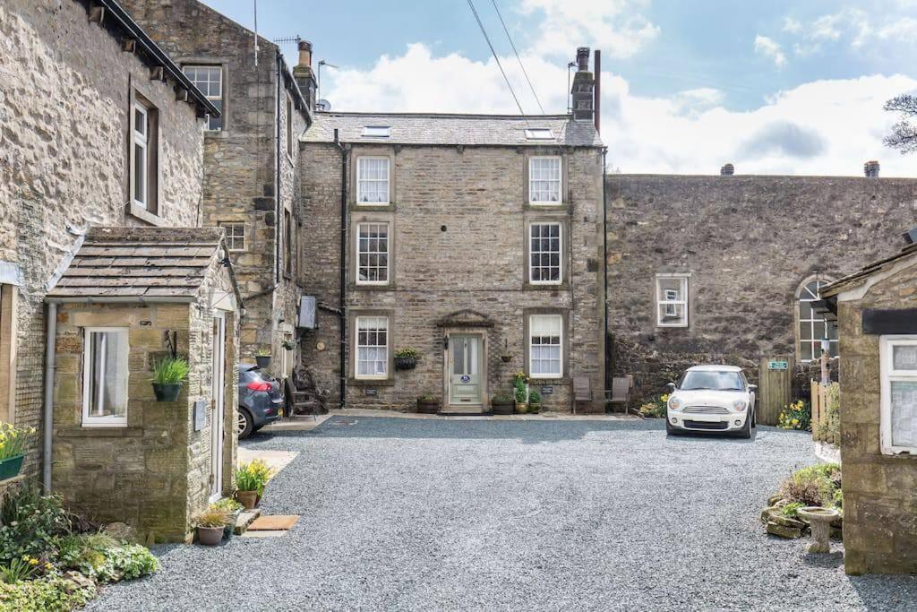 an old stone house with a car parked in the driveway at Fern Hse Grassington; central yet quiet & parking in Grassington