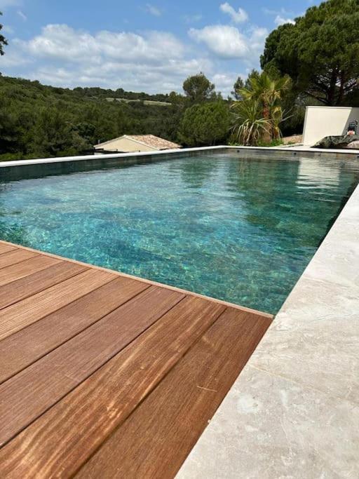 une grande piscine avec une terrasse en bois dans l'établissement VILLA AVEC PISCINE LA GARRIGUE, à Nîmes