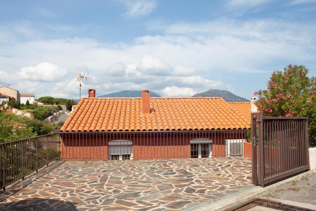 a red house with an orange roof and a gate at Villa Bougainvilliers in Banyuls-sur-Mer