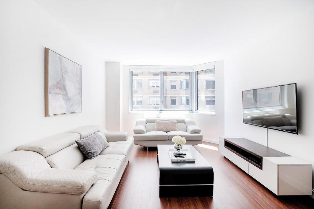 a white living room with a couch and a tv at Apartment with a beautiful view in New York