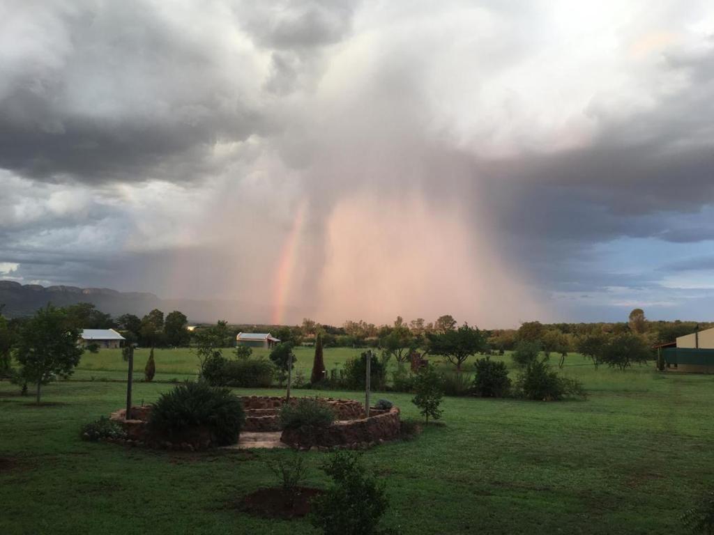 a rainbow in the sky over a green field at Votadini Country Cottages in Magaliesburg