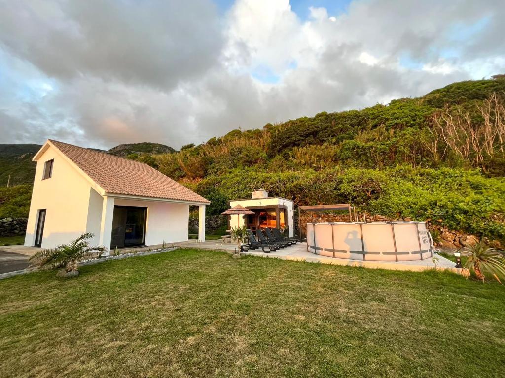 a white house with a hill in the background at Spot Milasmar in Faja Grande