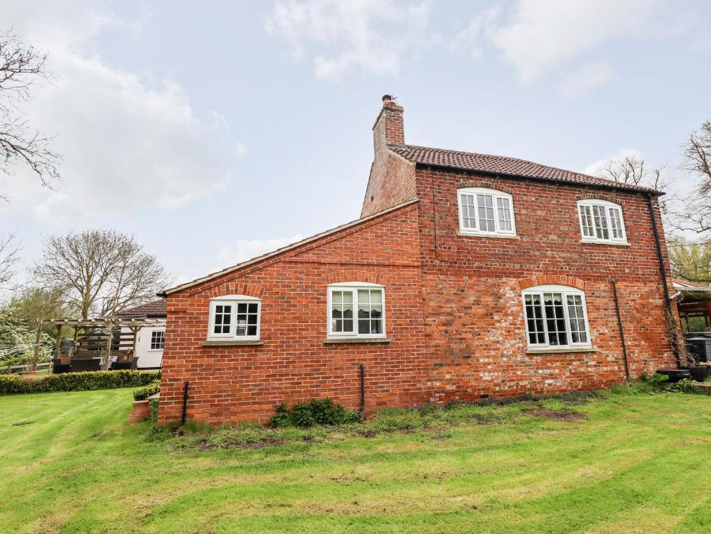 an old brick house with white windows on a field at Pat's Cottage in Market Rasen