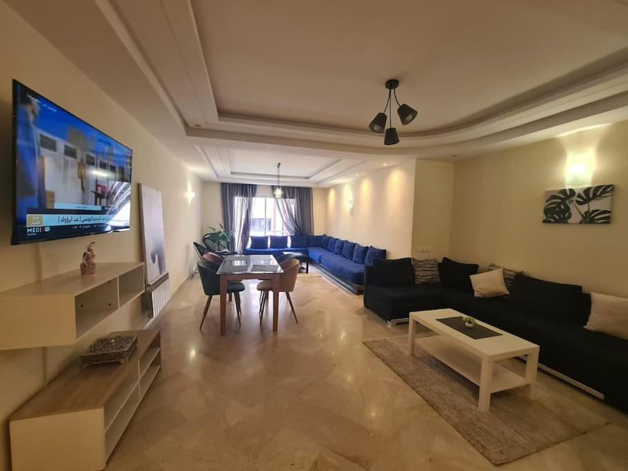 ein Wohnzimmer mit einem Sofa und einem Tisch in der Unterkunft Immense appartement familial lumineux haut de l Agdal in Rabat