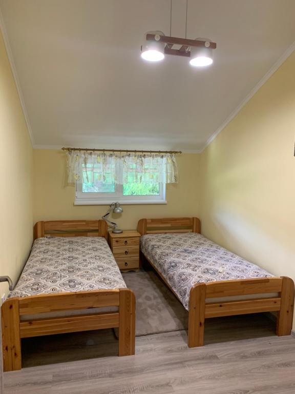 1 dormitorio con 2 camas y ventana en Лісова хатина, en Pilipets