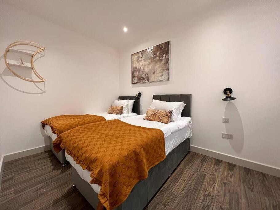 a bedroom with a bed with a orange blanket on it at Star London Finchley Road 1-Bed Sanctuary in London