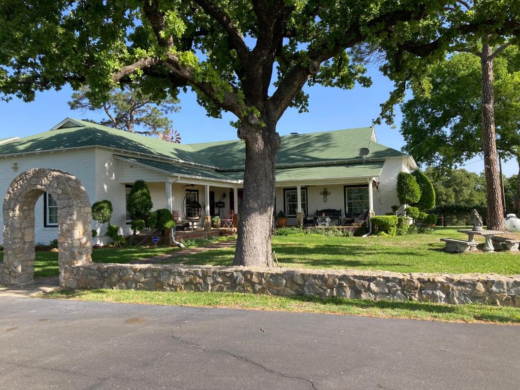 a white house with a tree in the yard at The Old Liberty Schoolhouse in Azle