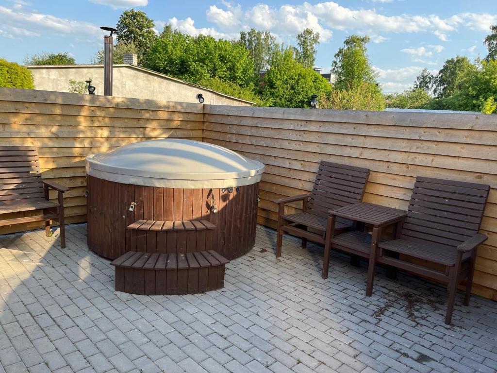 a wooden fence with two benches and a hot tub at Kotedža Tīkli in Bigauņciems