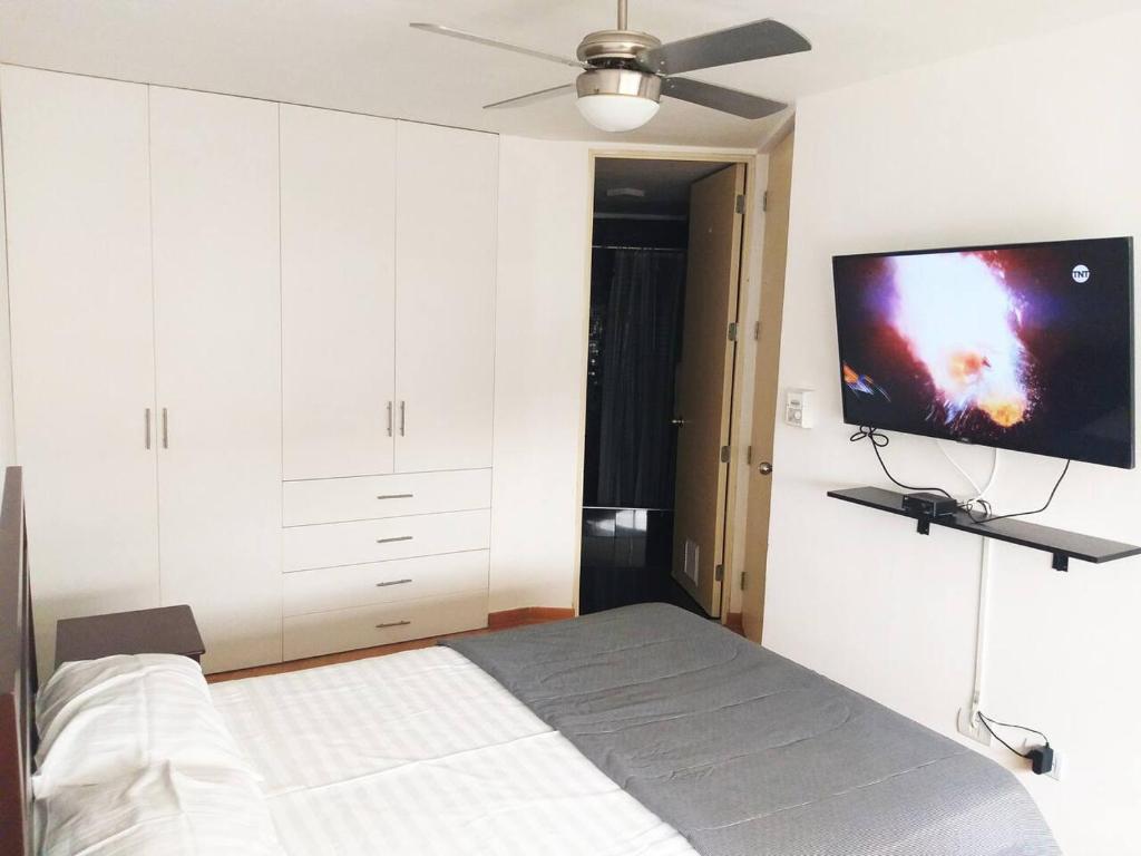 Schlafzimmer mit einem Bett und einem Flachbild-TV in der Unterkunft Departamento para un buen descanso in Lima