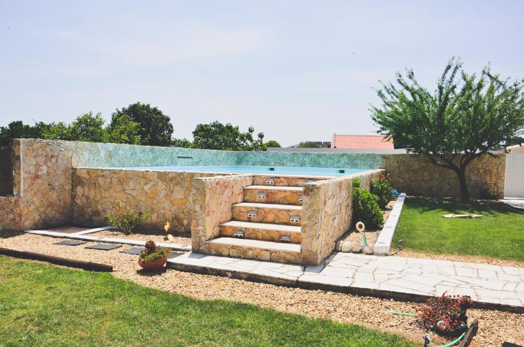 uma piscina num quintal com uma parede de pedra em Tree House - 3 Casas Figueira Laranjeira Limoeiro em Sesimbra