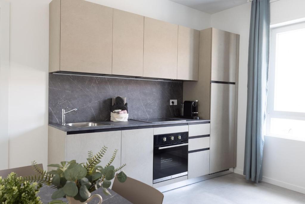 a kitchen with white cabinets and a sink and a stove at Bnbook Residenza Locatelli in Rho