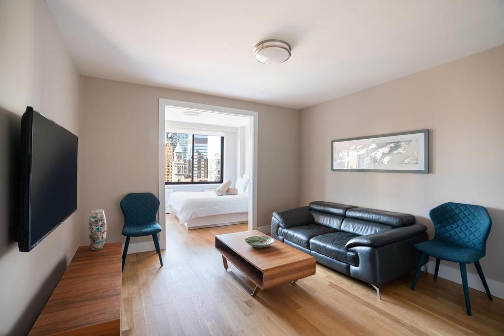 ein Wohnzimmer mit einem schwarzen Ledersofa und 2 Stühlen in der Unterkunft Apartment in Columbus Avenue in New York