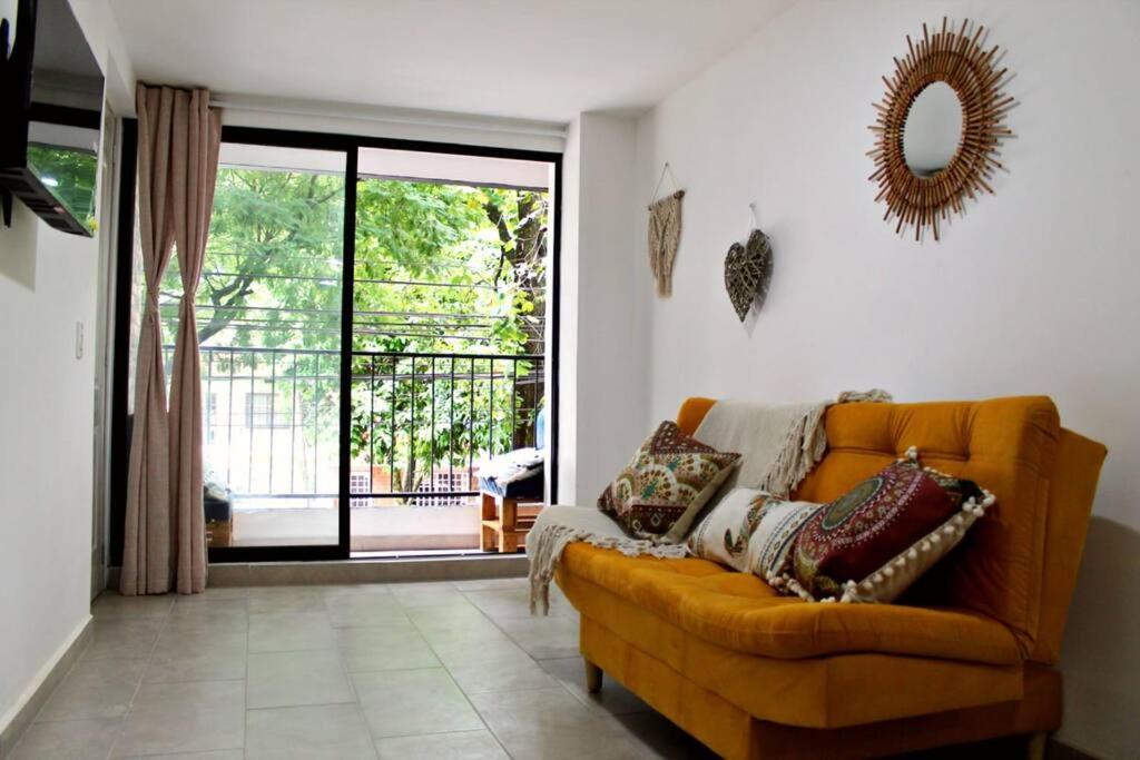 sala de estar con sofá y puerta corredera de cristal en Nativo House amplio y acogedo, en Medellín