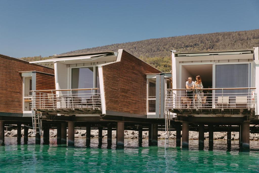 two people standing on a dock on the water at Hotel Palafitte in Neuchâtel