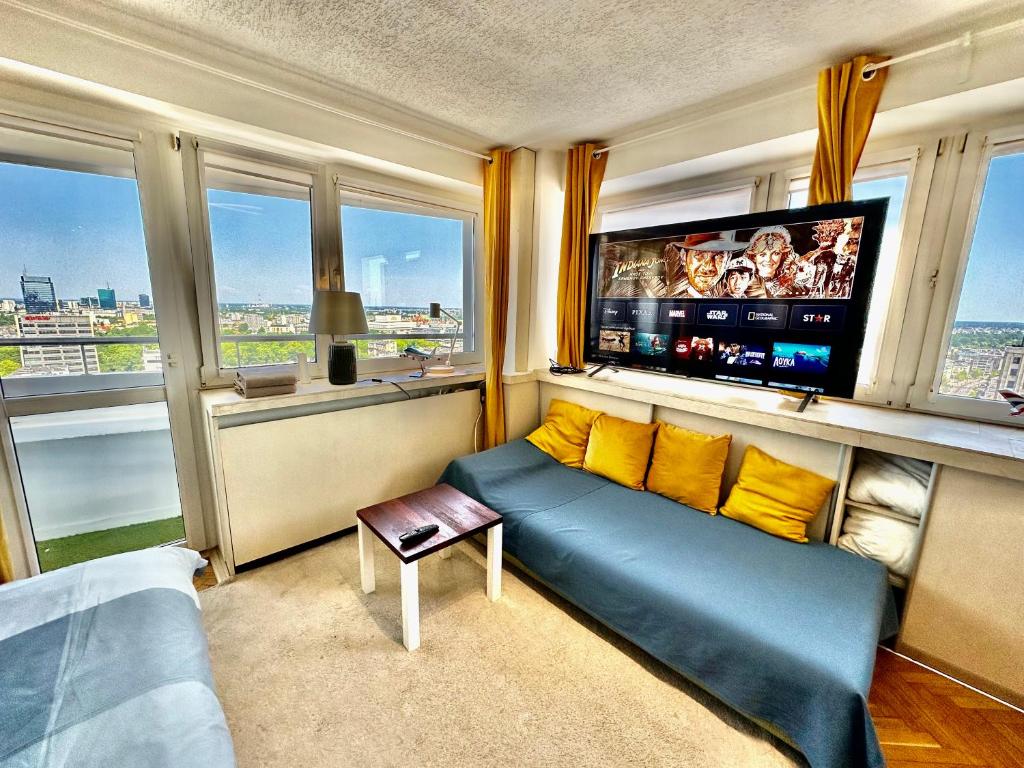 sala de estar con sofá y TV de pantalla plana en SUN clima/AC metro x2 Fast WiFi 500 Mbs 70’TV Netflix AppleTV HBO en Varsovia