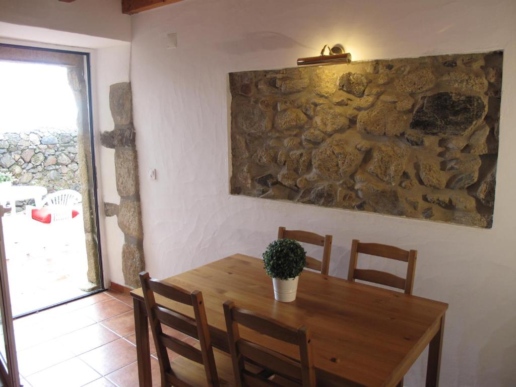 a dining room with a wooden table and a stone wall at Casa do Castelo - Muralha in Castelo de Vide