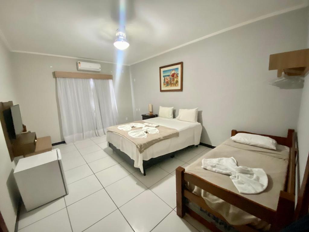 Habitación de hotel con 2 camas y TV en Pousada Bonanza, en Arraial do Cabo