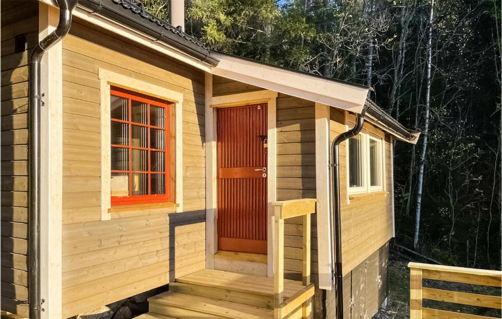 eine Holzhütte mit einer roten Tür und einer Treppe in der Unterkunft Lovely Home In Flateby With Kitchen in Flateby