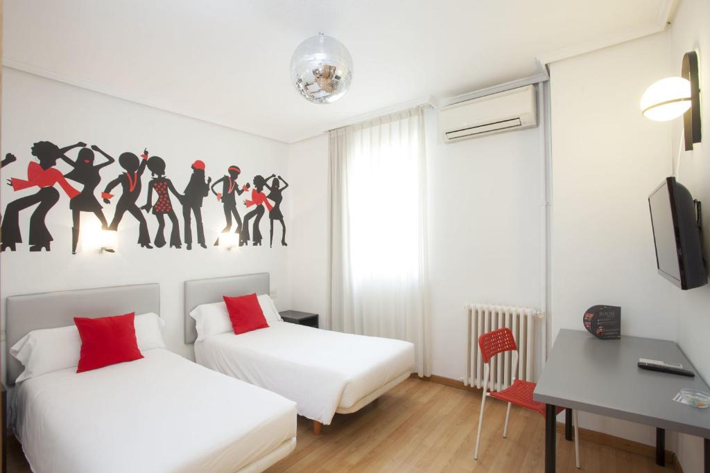 a hotel room with a bed, desk, and paintings on the wall at Casual de la Música Valencia in Valencia