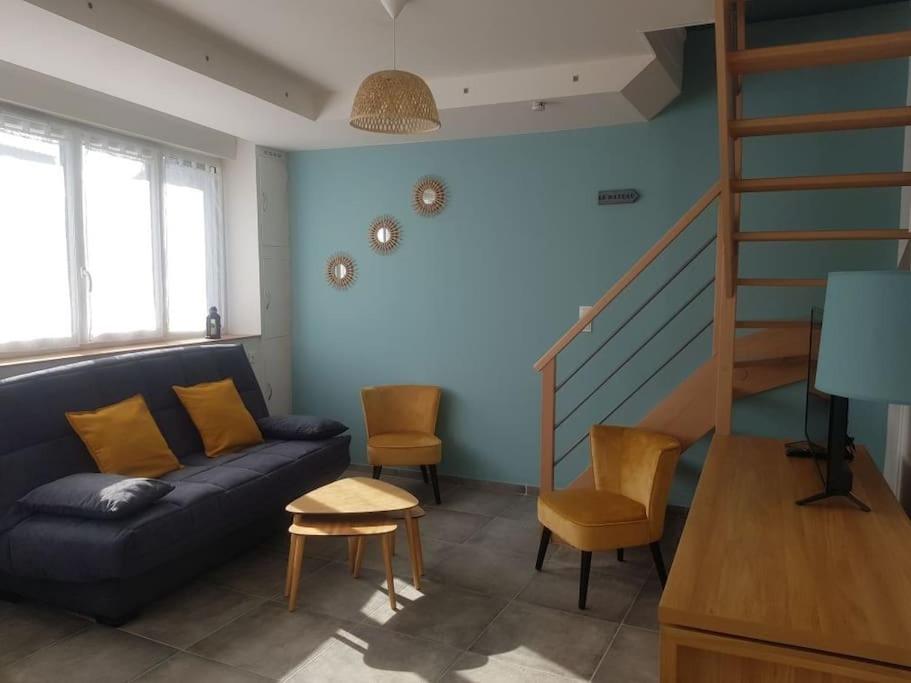 a living room with a couch and a staircase at Maison Bateau in Lion-sur-Mer