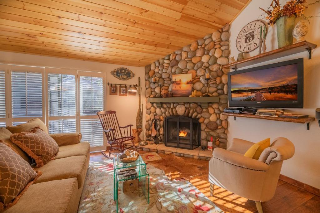a living room with a stone fireplace and a tv at Junipine Lakefront Condo - Walking distance to the lake! Less than 2 miles from the slopes! in Big Bear Lake