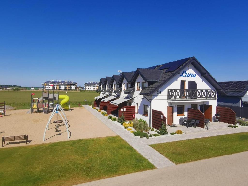 a building with a playground in front of a park at Domki LUNA in Sarbinowo