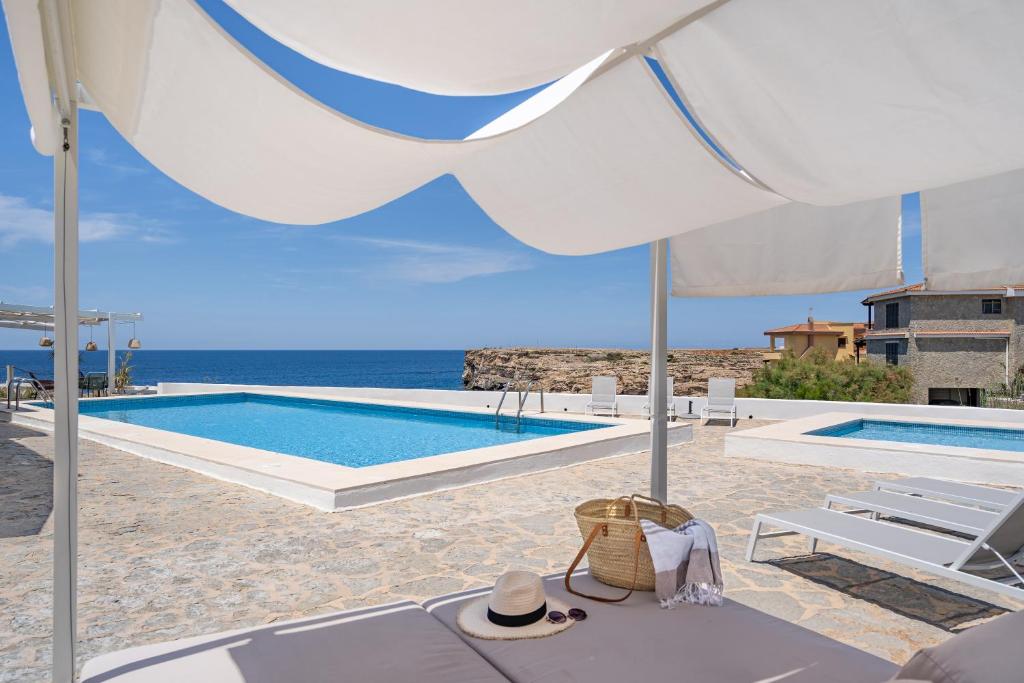 een witte parasol en een zwembad met uitzicht op de oceaan bij VORAMAR in Cala en Forcat