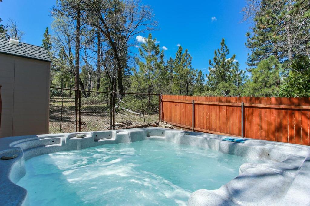 a hot tub in a backyard with a wooden fence at Little Brown Bear - Beautiful view, quiet area and an amazing hot tub! in Big Bear Lake