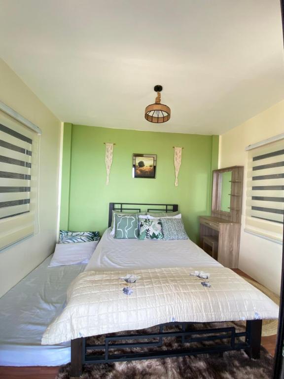 a bedroom with a large bed with green walls at Tanay Panoramic Mountain View Cabin 
