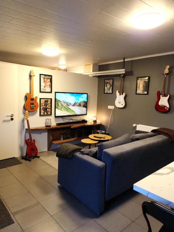 sala de estar con sofá azul y guitarras en la pared en Studio Seven 7, en Keflavík